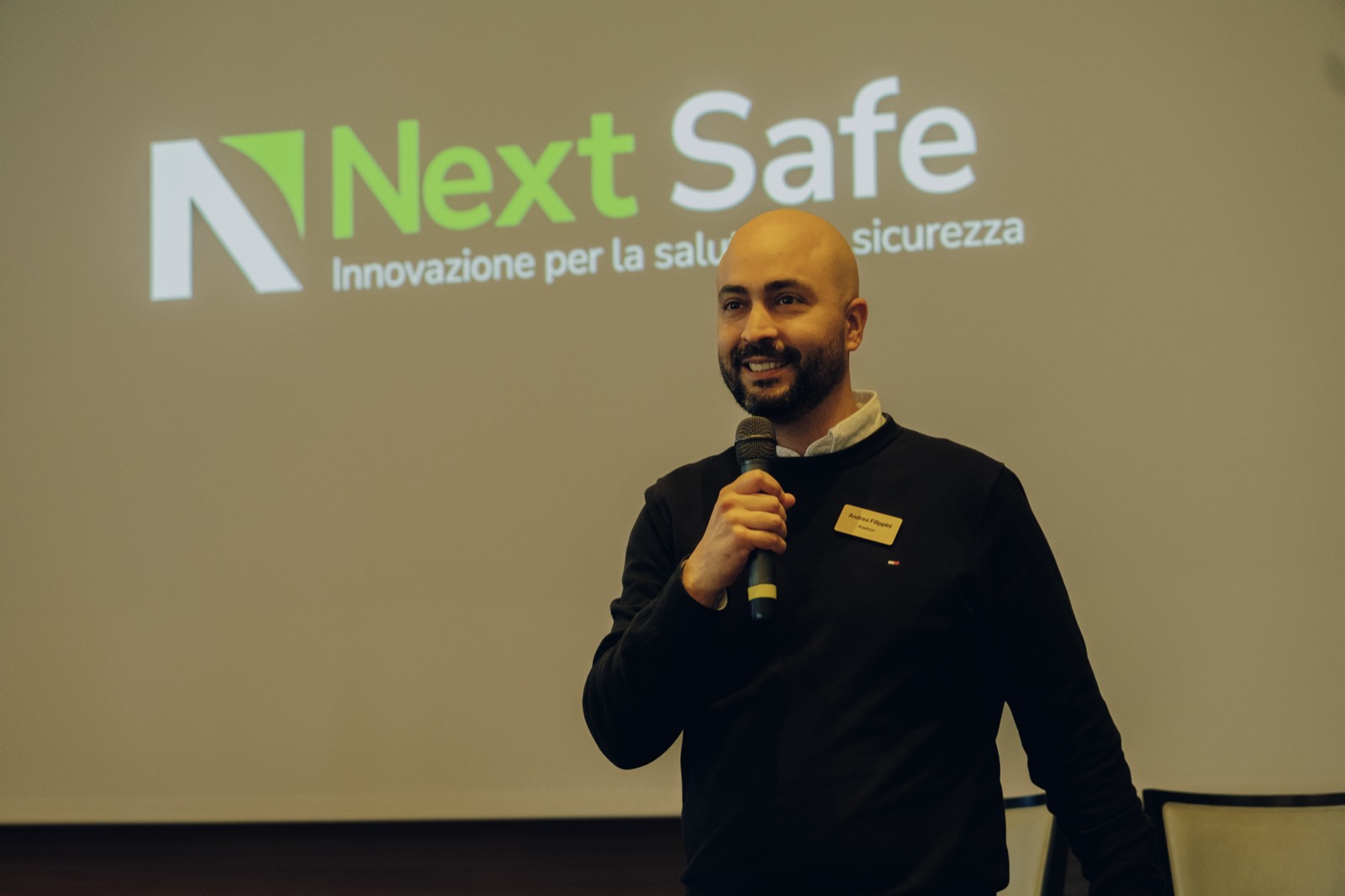 Un relatore sul palco davanti al logo Next Safe